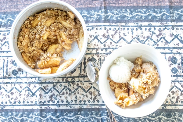 Bowl of instant pot apple crisp served with a scoop of vanilla ice cream.