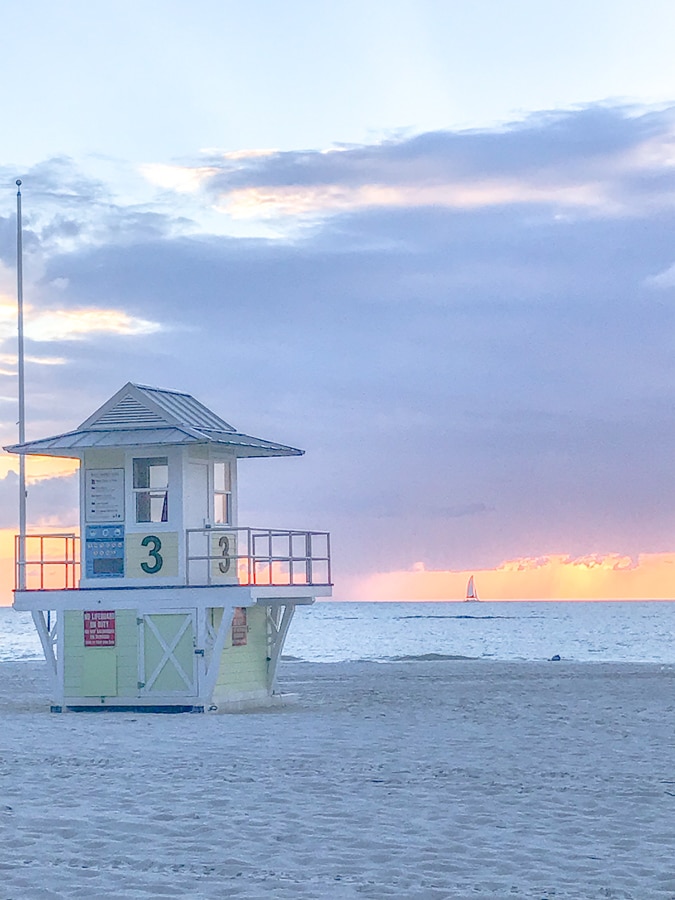 A yellow lifeguard tower on the sugar sand beach of Clearwater during sunset.