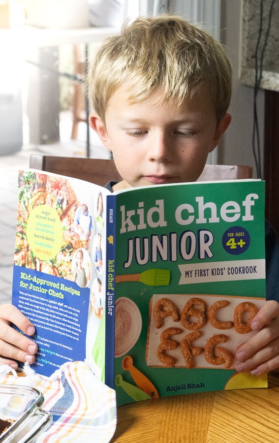 Boy reading the recipe for apple-cinnamon french toast bake in the kid chef junior cookbook.