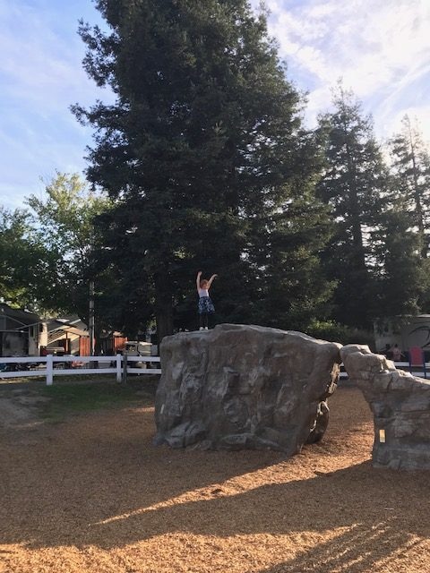 A 4-year-old-girl standing on a rock in the Petaluma KOA campground playground.