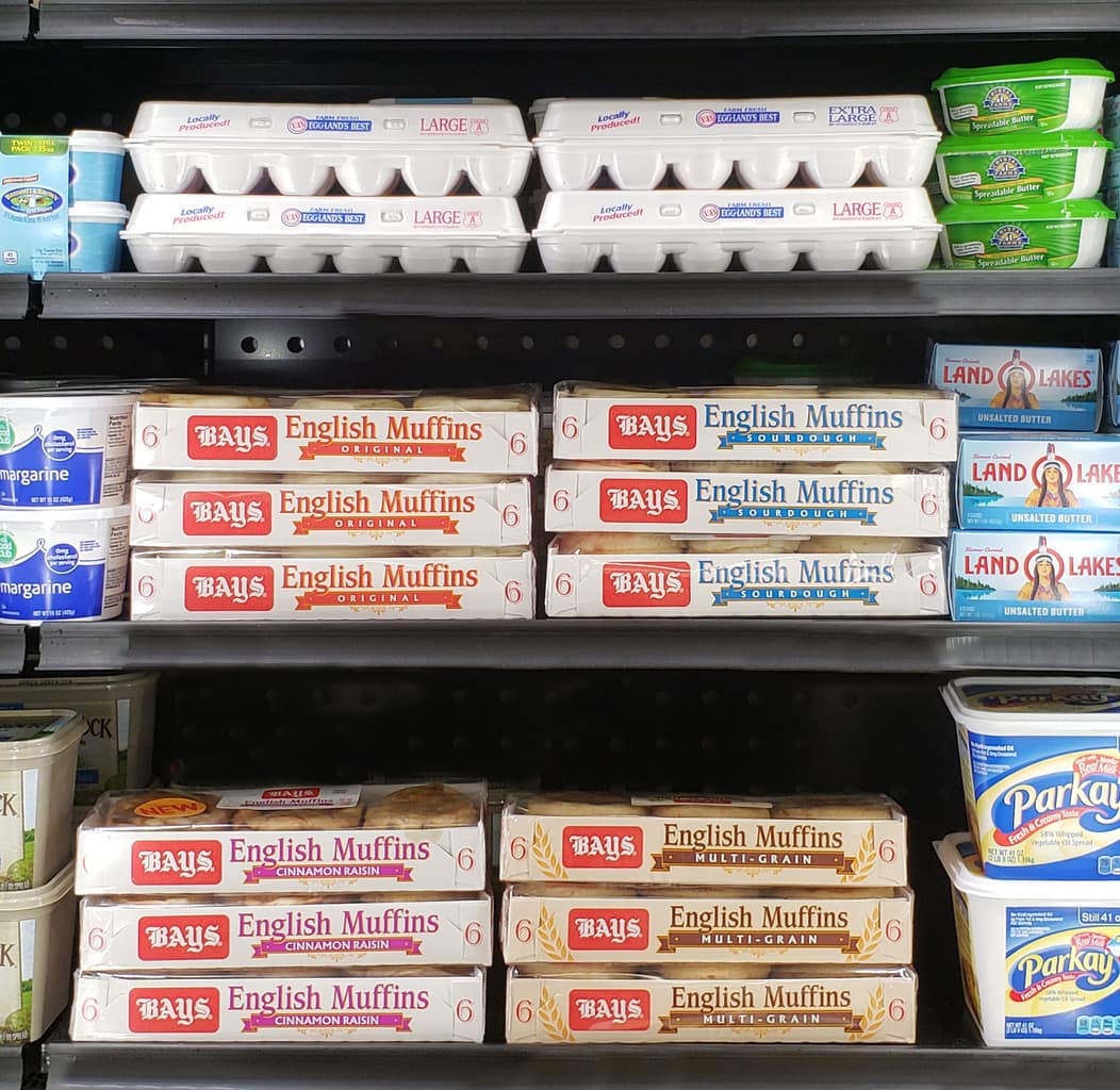 Bays English Muffins in the dairy case of a grocery store.