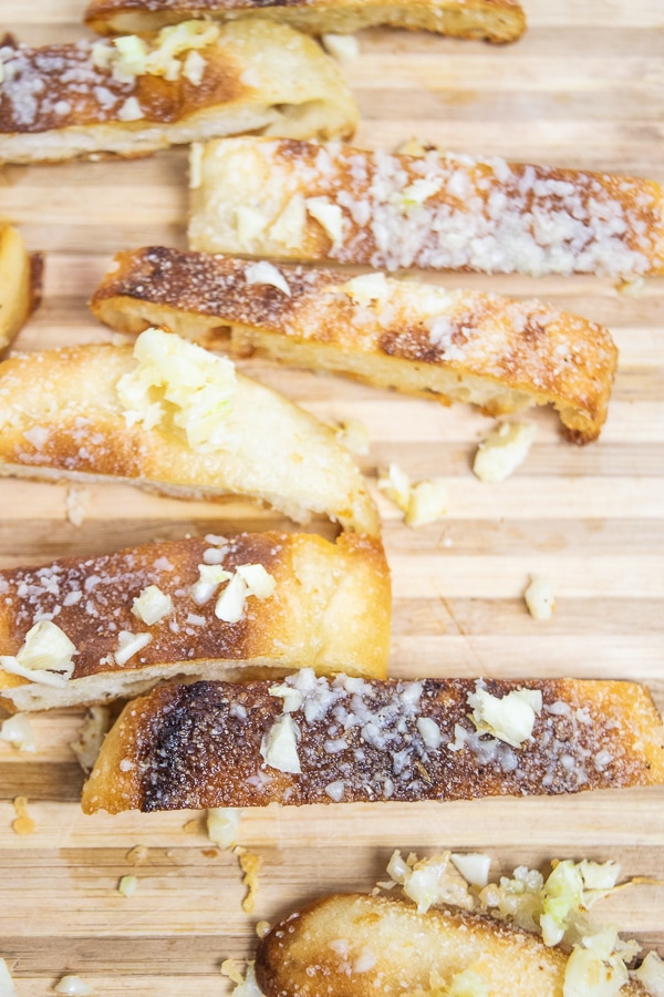 A close up shot of garlic and parmesan crisps on a cutting board.