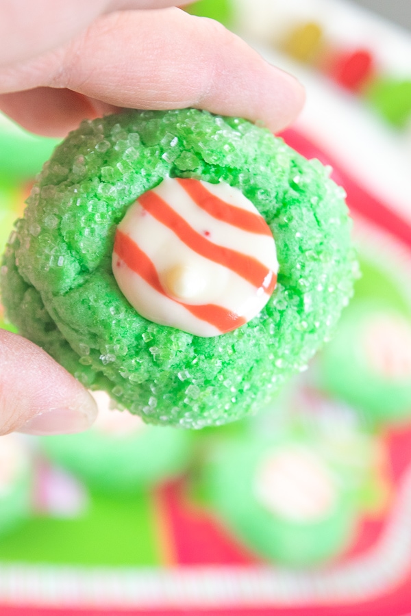 Add these Grinch Christmas Cookies to your list this year! These sparkly green cookies have a kiss "Santa hat" in the middle making them look just like The Grinch Who Stole Christmas!