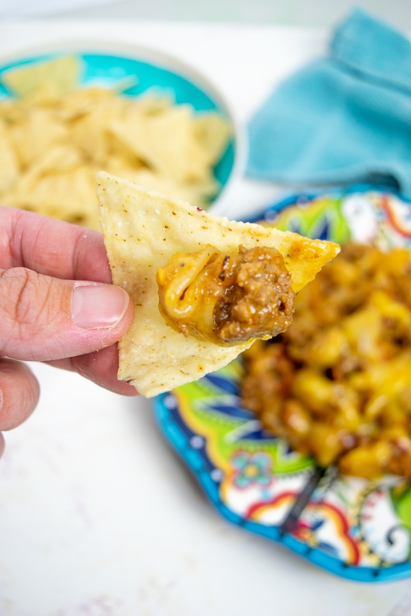 A close-up picture of a tortilla chip with a scoop instant pot cheesy taco pasta. 