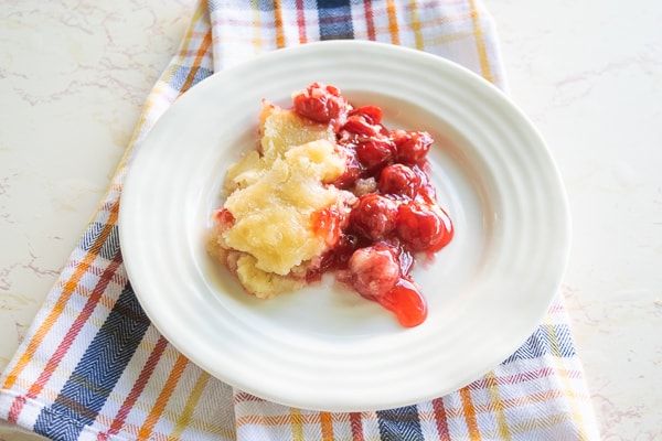 A close up of instant pot cherry cobbler on a small white plate.