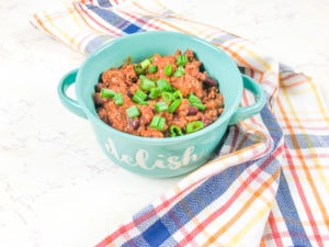 A bowl of instant pot beef chili topped with fresh green onions.