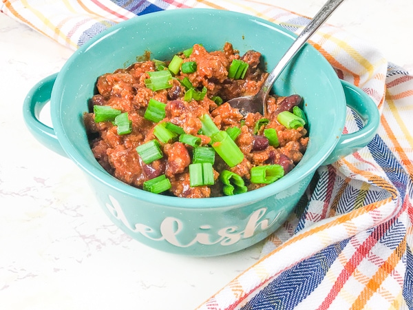 A bowl full of beef chili from the instant pot with a spoon scooping up a bite.