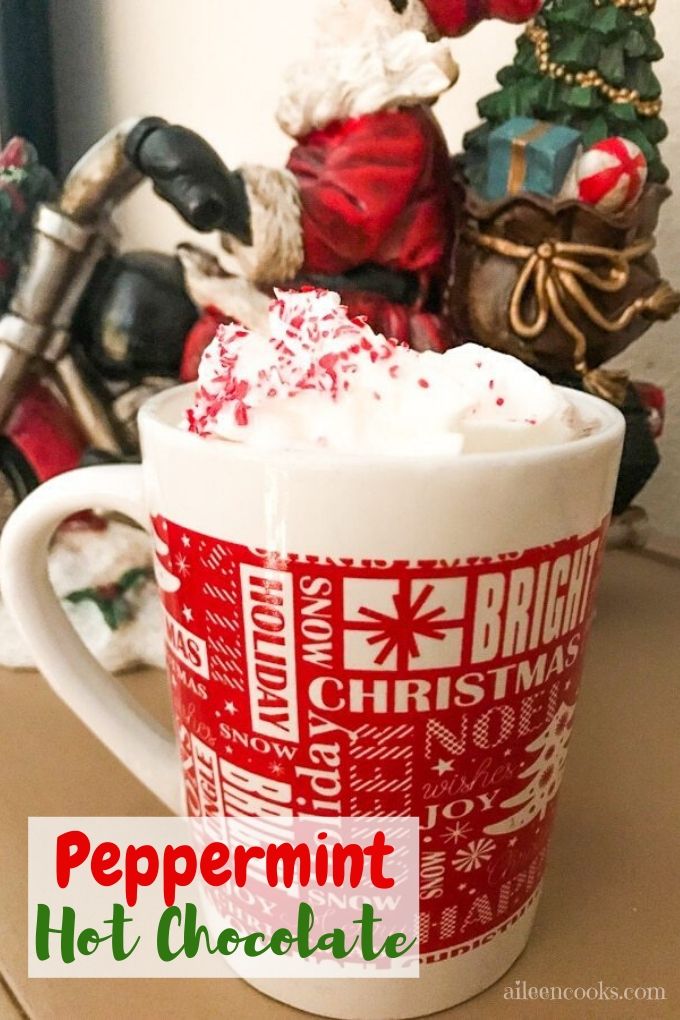 A cup of homemade peppermint hot chocoalte in front of a Santa figurine on a motorcycle.