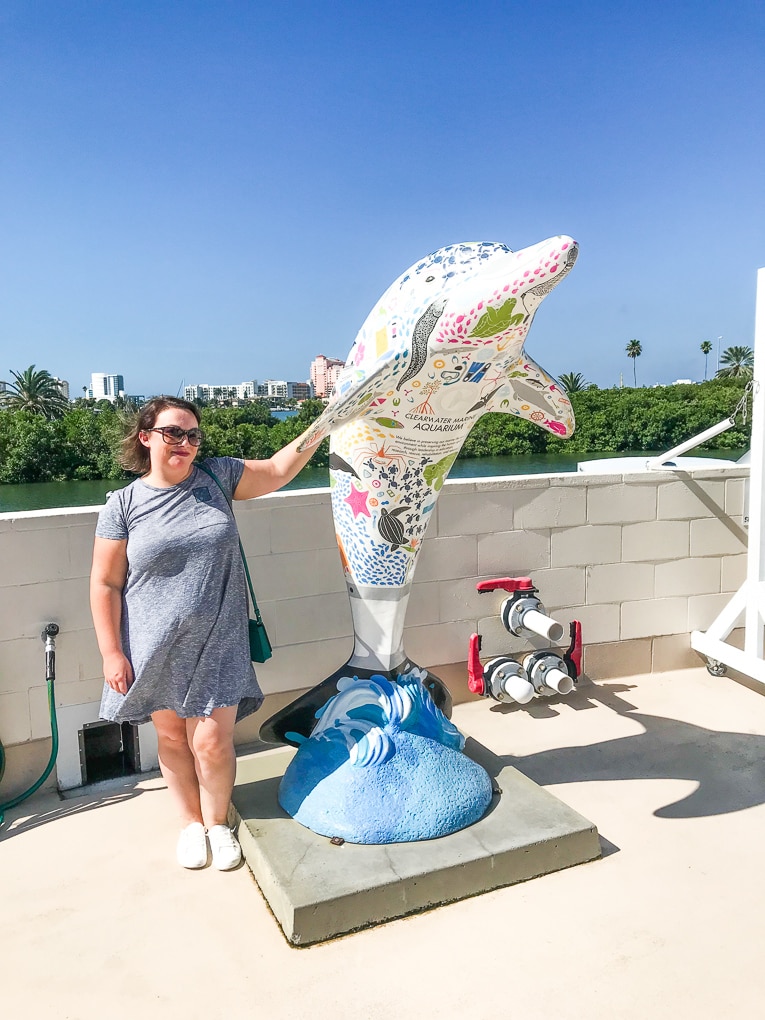 A woman standing next to a dolphin statue at the Clearwater Aquarium.