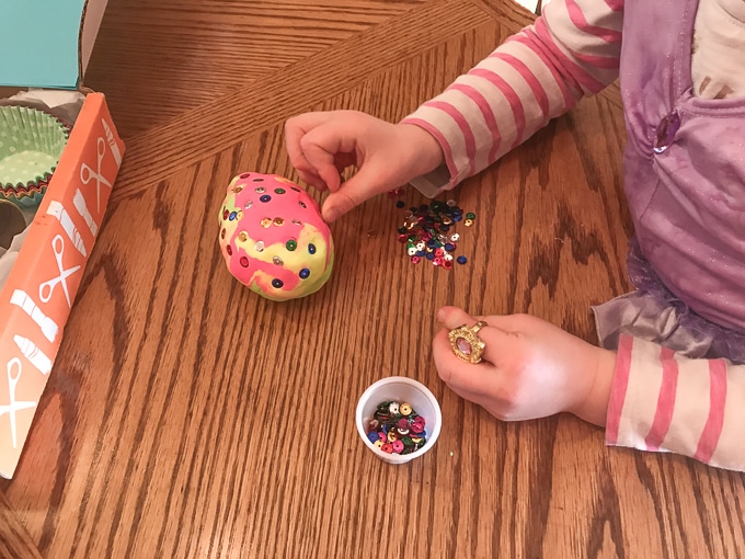 A child's hand decorating an egg made of clay.