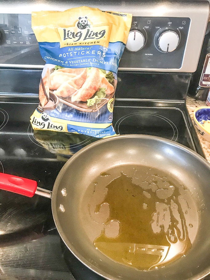 A pan of hot oil next to a bag of Ling Ling potstickers.