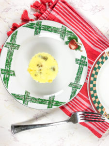An instant pot egg bit on a white and green plate next to a red striped towel.