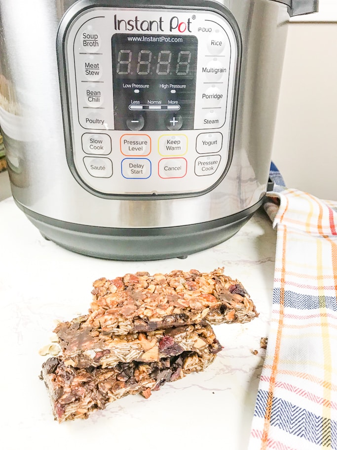 A stack of three granola bars in front of an instant pot.