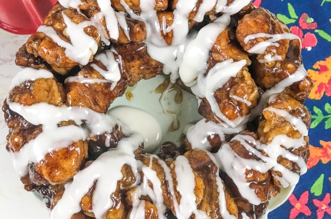 A fresh batch of instant pot monkey bread drizzled with icing and next to a floral hand towel.