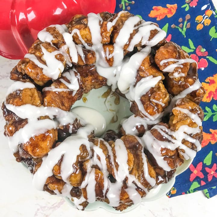 A fresh batch of instant pot monkey bread drizzled with icing and next to a floral hand towel.
