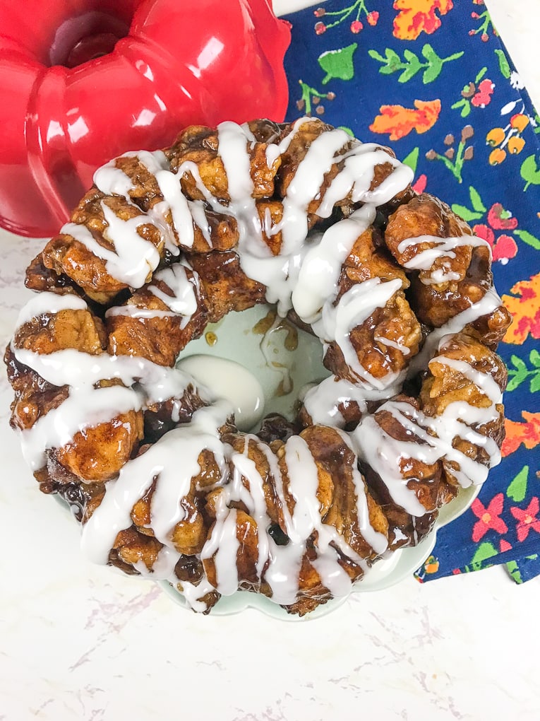 A fresh batch of instant pot monkey bread drizzled with icing and next to a floral hand towel.