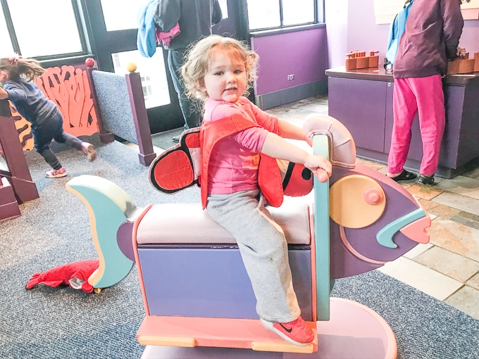 Toddler girl on a rocking fish at Monterey Bay Aquarium.