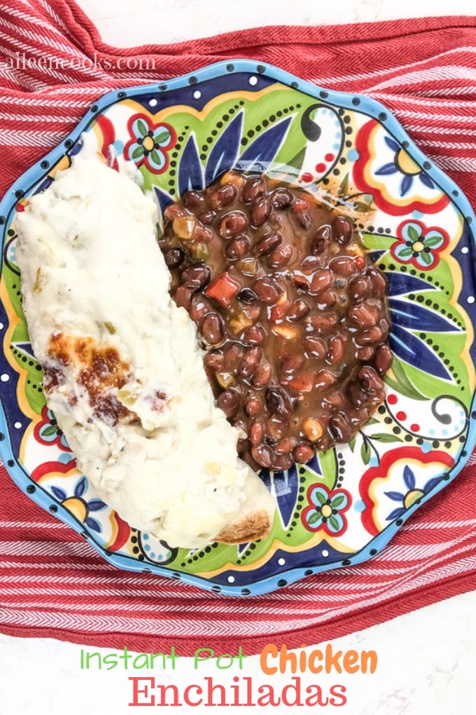 A festive plate on top of a red towel, filled with instant pot chicken enchiladas and beans.