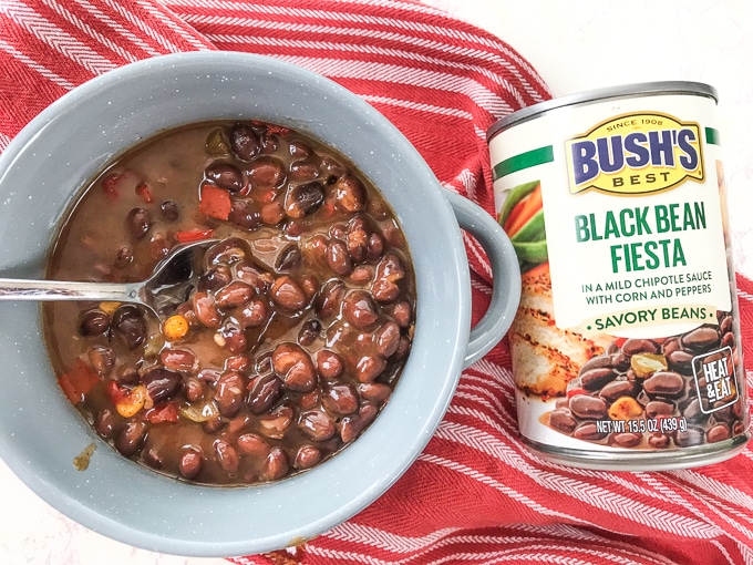 A grey bowl filled with beans next to a can of beans.