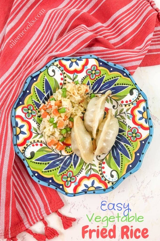 A colorful plate filled with fried rice and pot stickers, on top of a red striped towel.