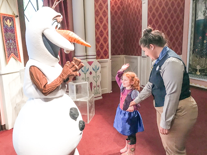 A little girl giving Olaf a high five during her trip to Disneyland in Winter.