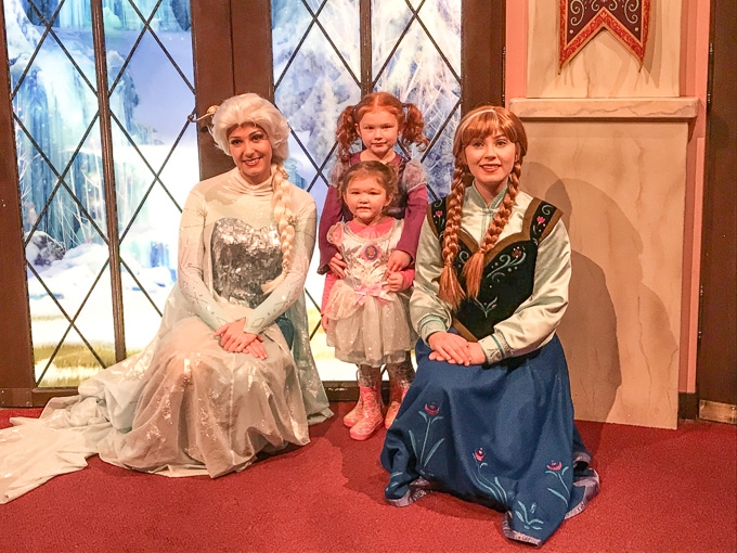 Two little girls standing next to Anna and Elsa from Frozen at California Adventure in Winter.