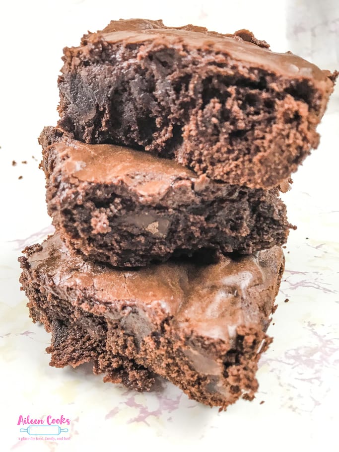 A triple stack of chocolate chunk brownies on a white marble counter top.