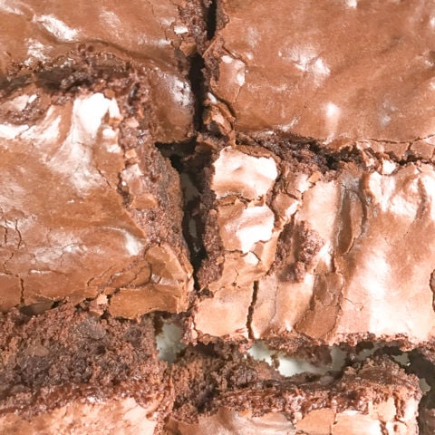 A close up of 6 frosted chocolate chunk brownies.
