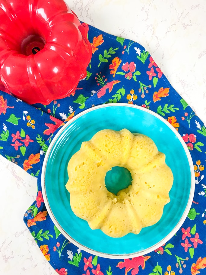 Instant pot cornbread on a blue plate next to a red bundt pan.