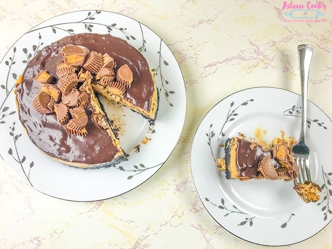 A plate of peanut butter cup cheesecake next to the entire cheesecake.