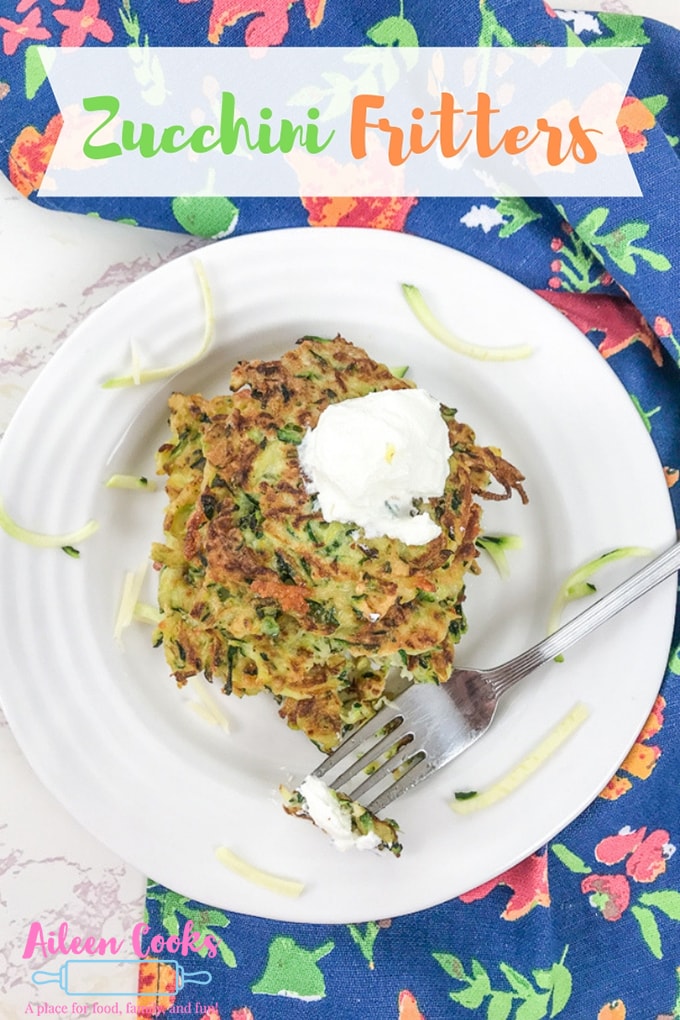 A plate of zucchini fritters with a fork holding a bite.