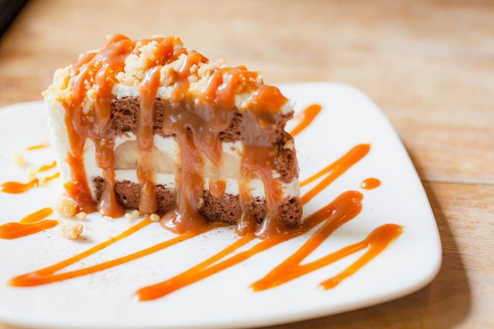 instant pot banoffee pie on a white plate and drizzled in caramel sauce.