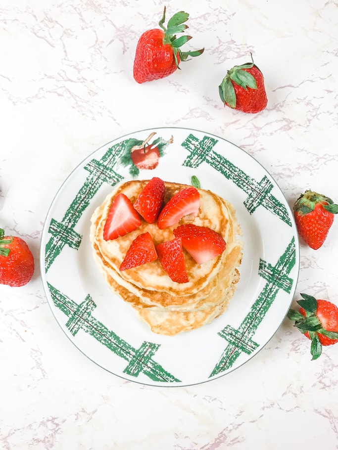 Overhead shot of pancakes topped with sliced strawberries.