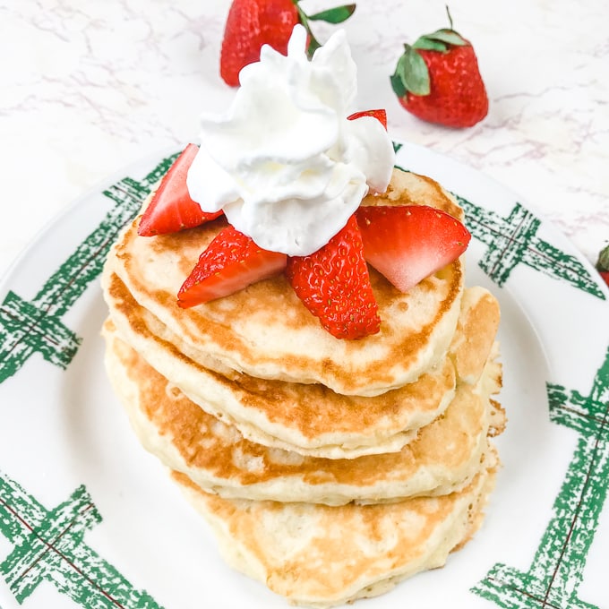 A stack of pancakes topped with strawberries and whipped cream.