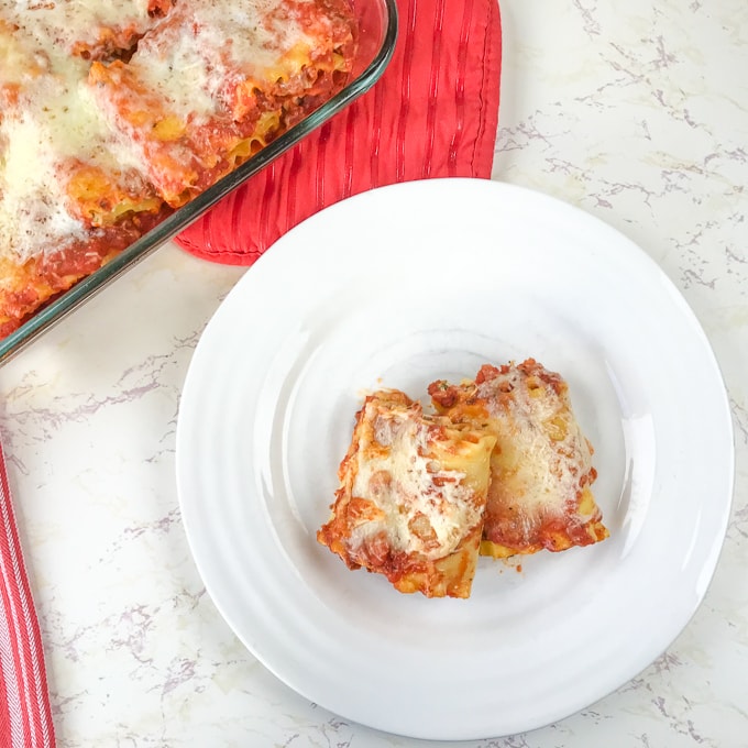 Two spinach lasagna roll-ups on a white plate.