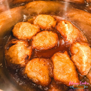 Apple dumplings coated in sauce, inside of instant pot.