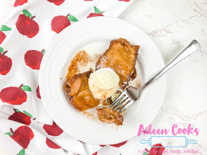 A plate of instant pot apple dumplings with a bite on a fork.