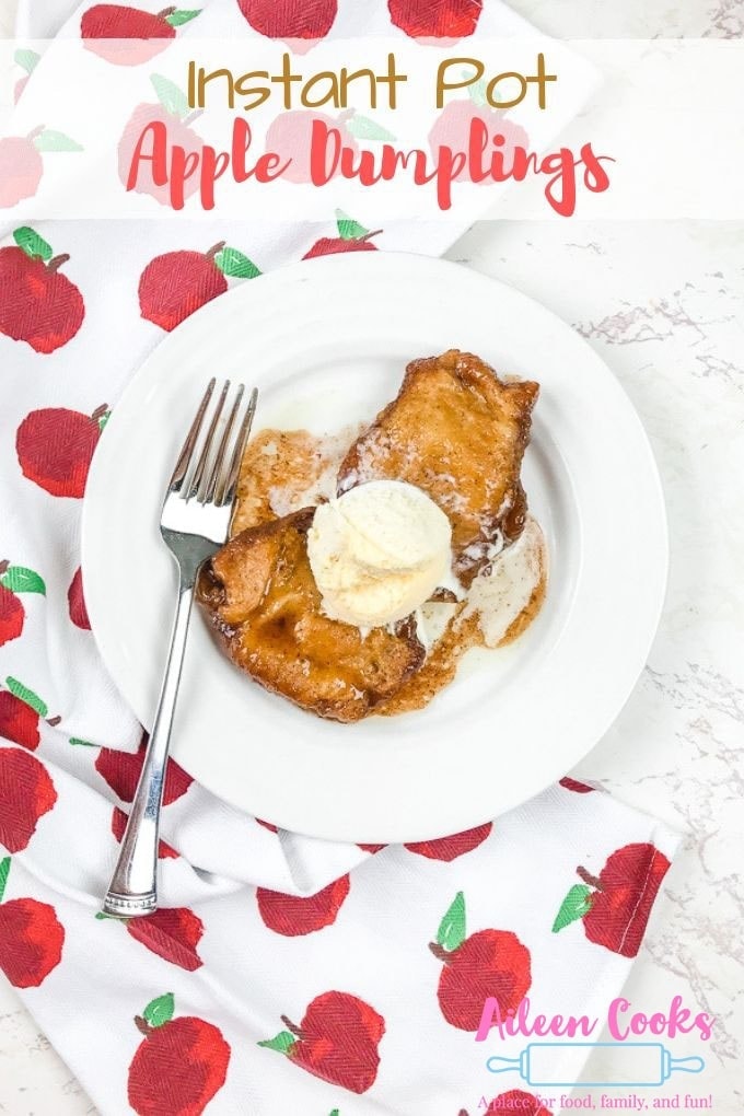 Instant pot apple dumplings on a white plate on top of a dish towel with red apples printed on it.