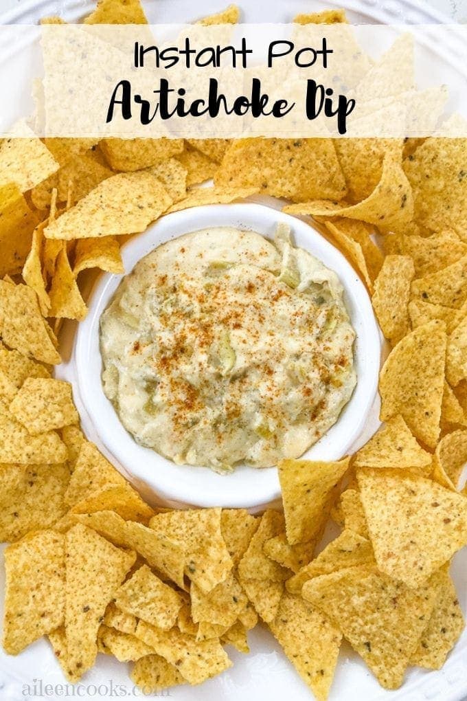 A bowl of instant pot artichoke dip surround by tortilla chips.