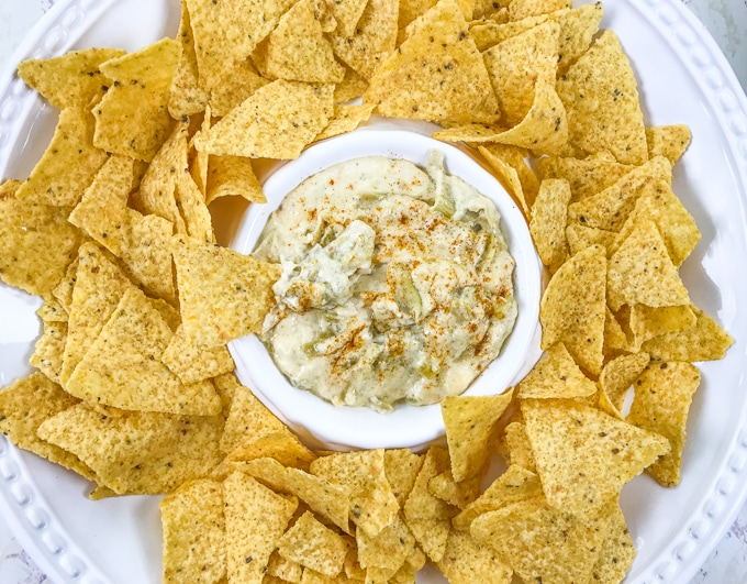 A bowl of instant pot artichoke dip with a chip sticking out of the top of the bowl.
