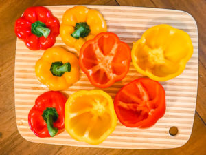 Red and yellow bell peppers with the tops sliced off.