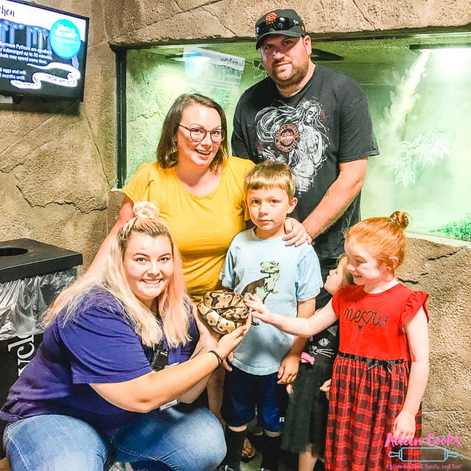 A family posing next to a ball python at SeaQuest Folsom.