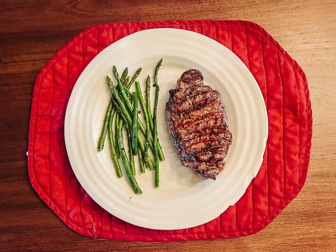 Steak and asparagas on a white plate.
