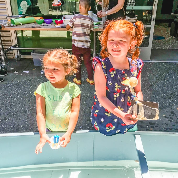 Two girls smiling with the boats they created.