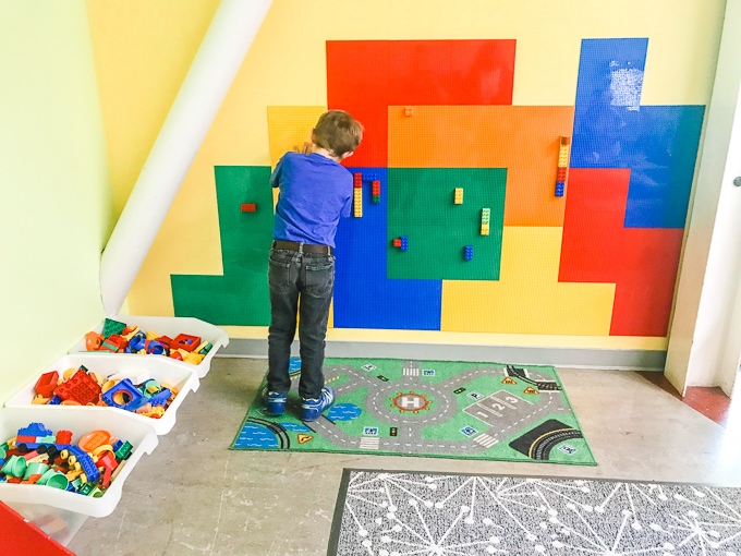 A boy building a creation on a LEGO wall.