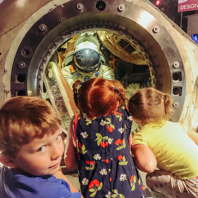 Three kids looking inside a Russian space module.