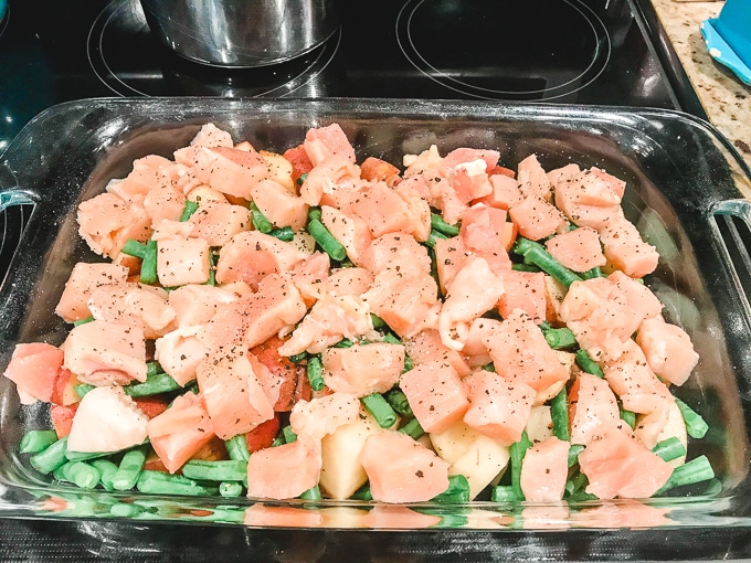 Green beans, potatoes, and chicken layered in a casserole dish.