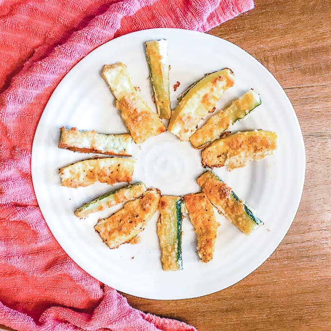 Close up of parmesan zucchini fries next to a red towel.
