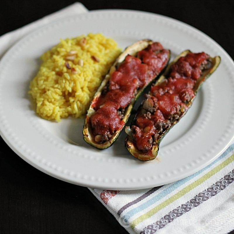 Two pieces of stuffed zucchini on a white plate.