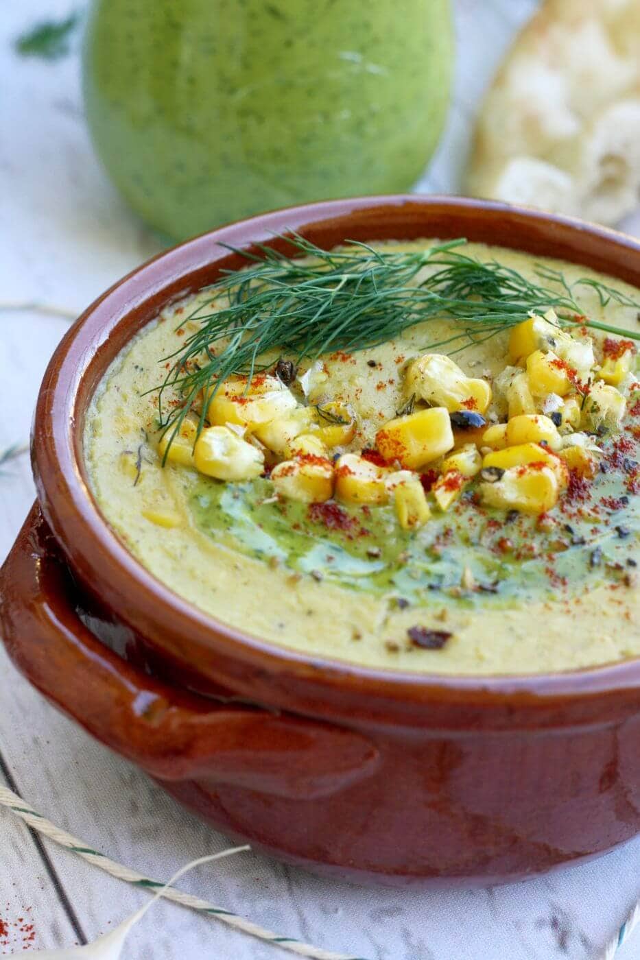 corn and zucchini soup in a red bowl.